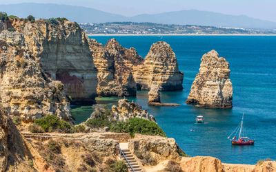 Clifftop view looking down at natural rock arches and crystal-clear water at Ponta da Piedade
