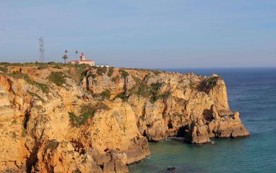 The white Ponta da Piedade lighthouse perched on the ochre headland above the sea