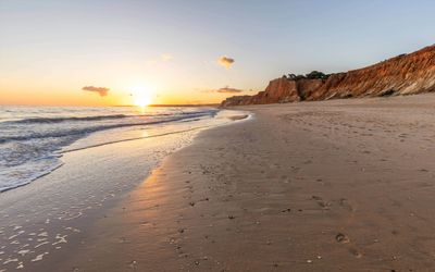 Late afternoon sun lighting the red sandstone cliffs at Praia da Falésia in deep amber tones