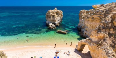 Ochre rock formations framing turquoise water at Praia de São Rafael, west of Albufeira