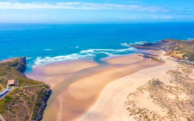 Waves crashing on the sandy shore of Praia da Amoreira
