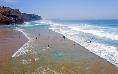 Surfers walking toward the waves at Praia de Vale Figueiras