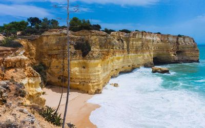 Sculpted ochre limestone arches and fallen boulders at the eastern end of Praia da Marinha