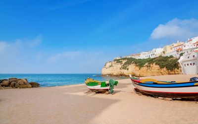 Colourful traditional fishing boats resting on the golden sand of Praia do Carvoeiro