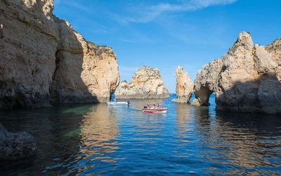 Small tour boat approaching a hidden cove through the rock formations at Ponta da Piedade