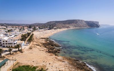 Aerial view of Praia da Luz with the dark Rocha Negra contrasting against golden limestone cliffs