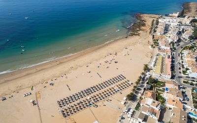 Aerial view of Praia da Luz from the sea showing the golden sand curving from the Rocha Negra toward the village