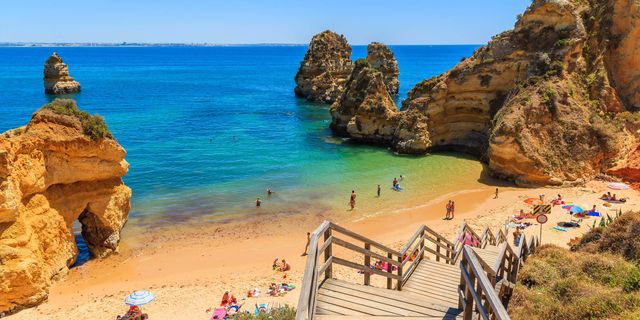 Praia do Camilo - A golden cove between ochre cliffs with a grotto tunnel at low tide