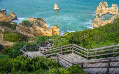 Wooden staircase winding down through the cliffs to Praia do Camilo