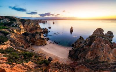 Warm sunset light on the golden cliffs surrounding Praia do Camilo