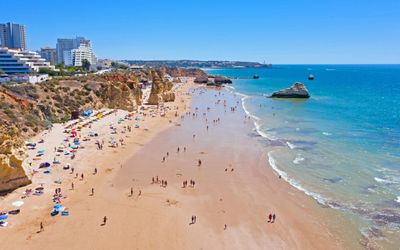 Wide stretch of Praia da Rocha beach with beachgoers and sea stacks