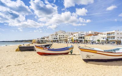 Colourful traditional wooden fishing boats on the sand with the whitewashed town and promenade in the background