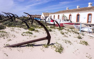 The restored tuna fishing village at Praia do Barril with traditional white buildings and anchors in the foreground