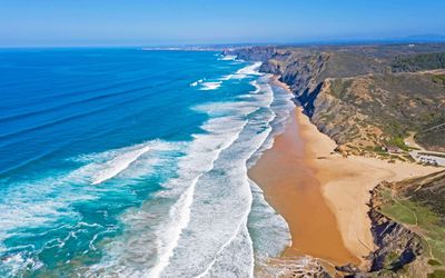 Praia da Cordoama stretching below towering black cliffs