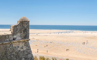 View of Cacela Velha fortress church from the beach across the turquoise lagoon waters