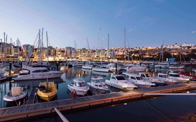 Colourful buildings in pink, orange, and blue lining Albufeira Marina with moored boats