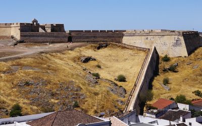 Forte de São Sebastião with its star-shaped walls and entrance gate seen from the castle hill across dry grassland