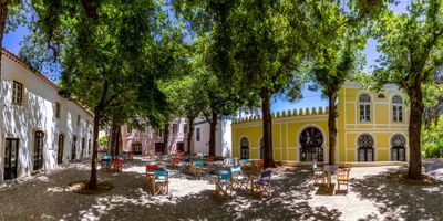 Shaded town square in Monchique with colourful café tables under leafy trees