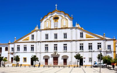 White and gold baroque facade of the Jesuit College Church in Portimão with its ornate pediment and cross