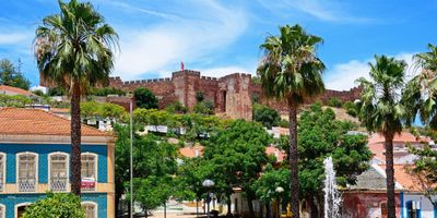 Silves Castle rising above the historic town with palm trees and traditional buildings