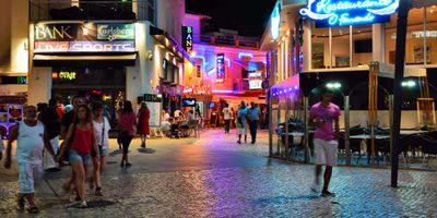 Neon-lit bars and clubs along The Strip in Albufeira at night