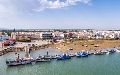 Fishing boats moored along the Cabanas de Tavira waterfront at low tide