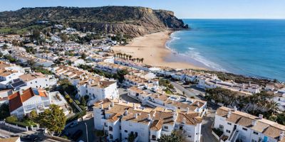 Sandy beach at Praia da Luz with the dark Rocha Negra volcanic outcrop rising from the shoreline