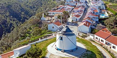 Aerial view of Odeceixe with its restored windmill and whitewashed houses with terracotta roofs tumbling down the hillside