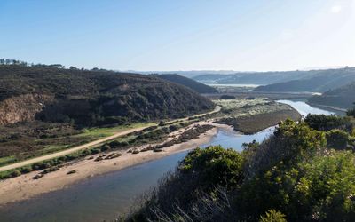 The Seixe River valley winding through hills with a walking path along the riverbank